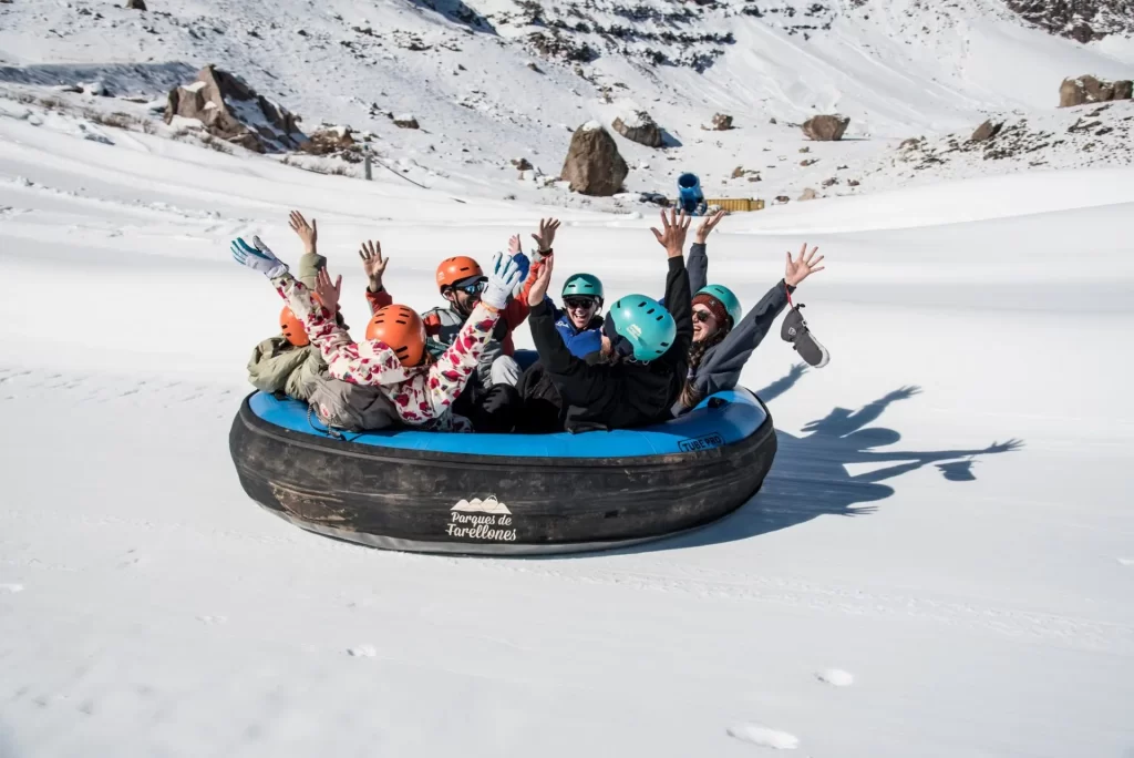 Diversión familiar en la nieve: Bajada en trineos y balsas inflables en Farellones, la actividad más popular del tour privado desde Santiago.